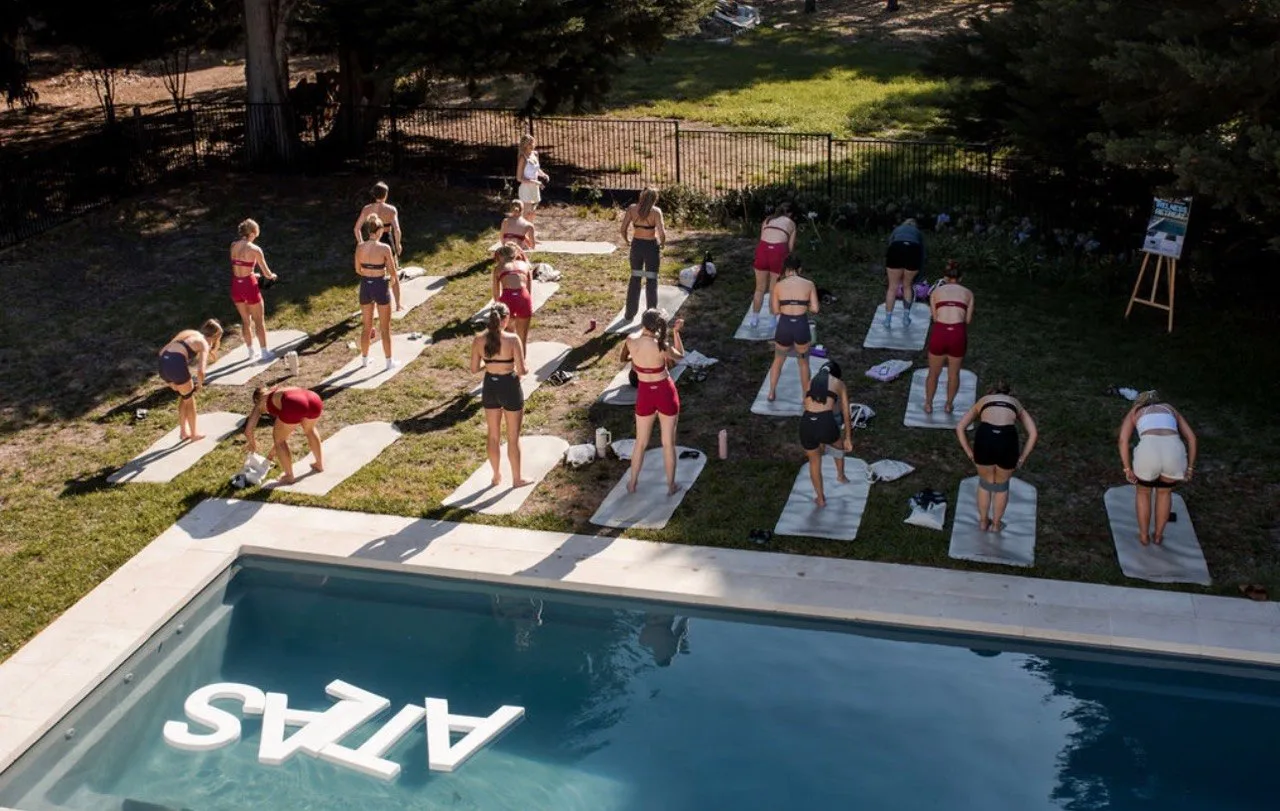 Outdoor group Pilates class beside an Atlas pool